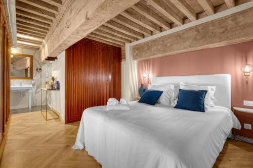 a bedroom with a large white bed with blue pillows at Les Relais du Capitole - Appartements d'hôtes in Toulouse