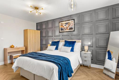 a bedroom with a large bed with a blue blanket at Stylish group retreat with garden, games & parking in West London in Staines