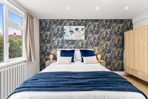 a bedroom with a large bed with blue sheets at Stylish group retreat with garden, games & parking in West London in Staines