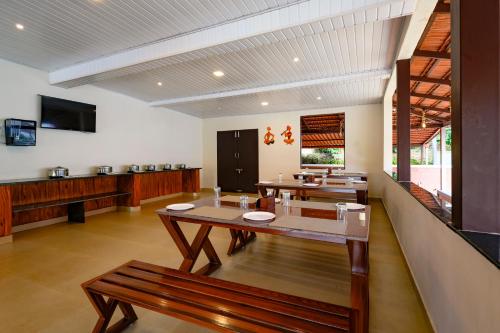 a dining room with a table and two benches at Bhuthanakadu Retreat Homestay Chikamagalur in Mudigere