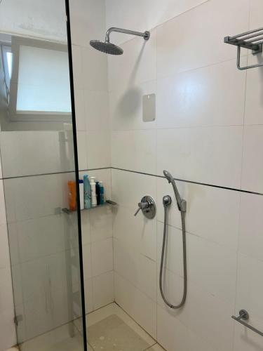 a bathroom with a shower with a glass door at The Urban Retreat by IsrApart in Ra‘ananna