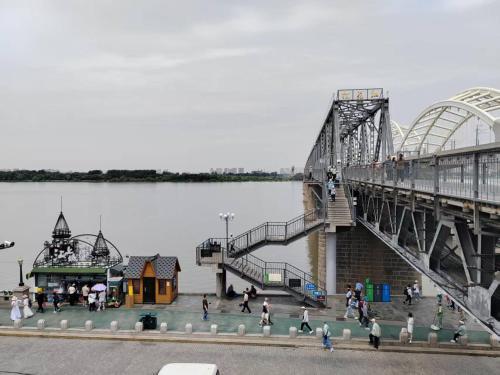 a bridge over a body of water with people walking around at Central Street River View Apartment in Harbin