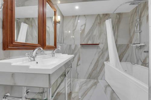 a white bathroom with a sink and a tub at Les Relais du Capitole - Appartements d'hôtes in Toulouse