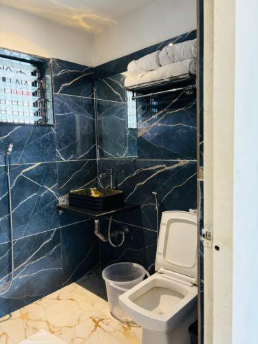a bathroom with a toilet and a blue tiled wall at Valley Vista 3BHK Pool Villa in Igatpuri