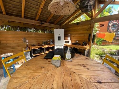 een grote houten tafel in een buitenkamer bij Caraiba - Maisons de Vacance avec Piscine et Toit Terrasse in Sainte-Anne