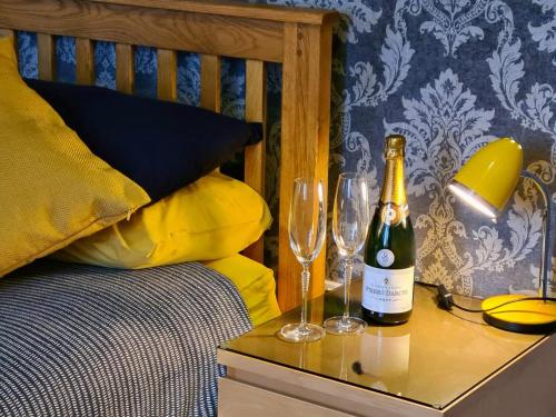 a bed with two glasses and a bottle of wine on a table at Swift Host - Owl Barn - Sleeps 2 - EV Charger - Pet Friendly in Loddon