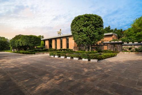 a building with a tree in the middle of a courtyard at Taj Damdama Lake Resort & Spa, Gurugram in Gurgaon