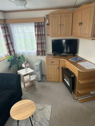 a living room with a couch and a table and a tv at Skye Holiday Caravan 4 in Uig