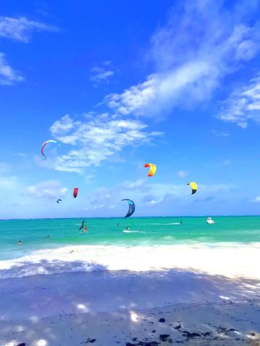 a group of people flying kites on the beach at Karibu House Paje in Paje