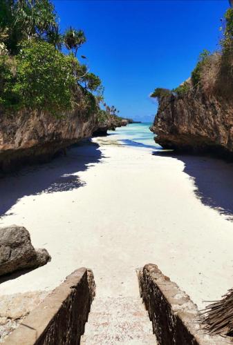 a view of a beach with rocks and the ocean at Karibu House Paje in Paje