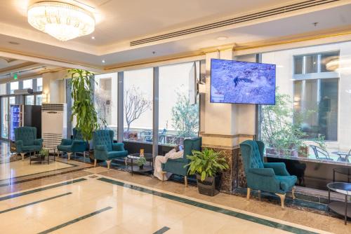 una sala de espera con sillas y una pantalla de proyección en Sapphire Plaza Hotel, en Doha