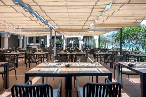 a restaurant with wooden tables and chairs and tablesearcher at Riu Palace Zanzibar - All Inclusive in Nungwi