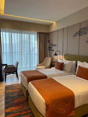 a hotel room with two beds and a chair at Ramada Encore by Wyndham Gurugram Dwarka Expressway in Gurgaon