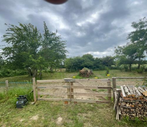 a wooden fence in a field with trees in the background at Camping Voi-la-la-vie in Saint-Christophe-en-Boucherie