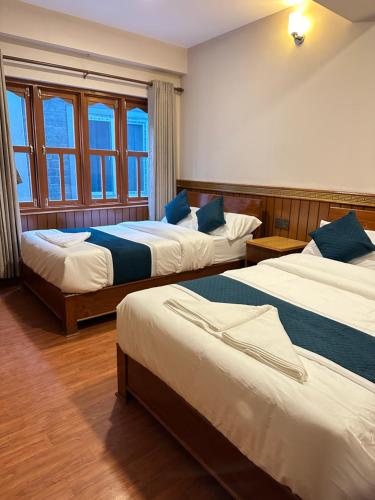 a hotel room with three beds and a window at Hotel Caravan in Muktināth