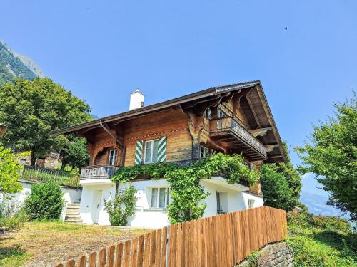 a wooden house on a hill with a fence at Chalet Haus am See by Interhome in Niederried
