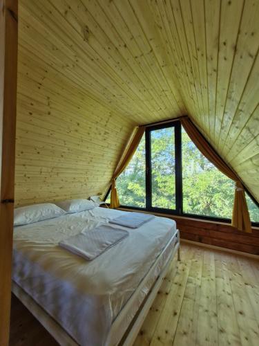 a large bed in a wooden room with windows at Cozy Cottage A in Kutaisi
