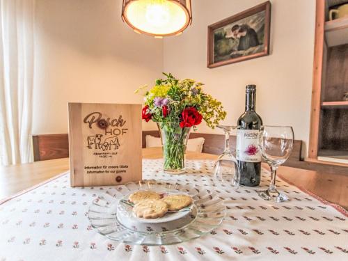 a table with a plate of cookies and a bottle of wine at Apartment Alpenfarm Poschhof by Interhome in Kaunerberg