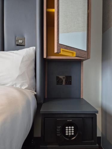 a bedroom with a bed and a nightstand with a clock at Point A Hotel London Westminster in London