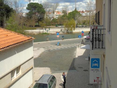 a woman walking down a street next to a building at Hotel Cavaleiros De Cristo in Tomar