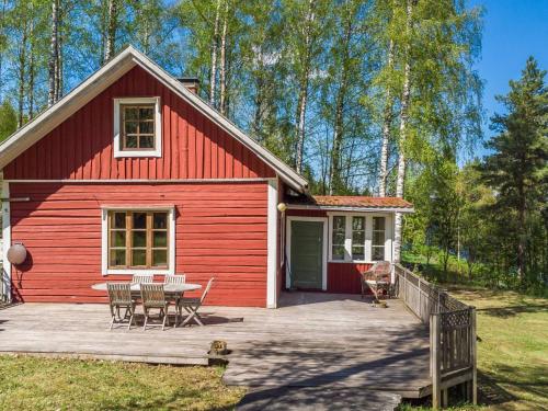 een rood huis met een tafel en stoelen op een terras bij Holiday Home Koivikko by Interhome 