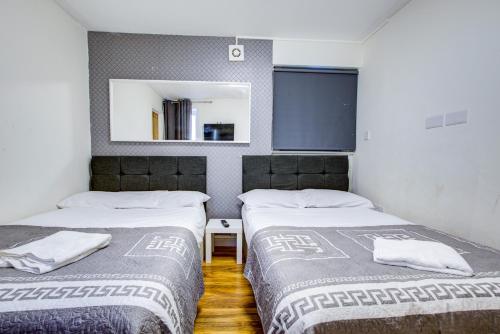 two beds in a room with a mirror at Willmore Hotel in London