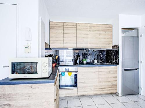 a kitchen with wooden cabinets and a microwave at Apartment Atrium by Interhome in Caves