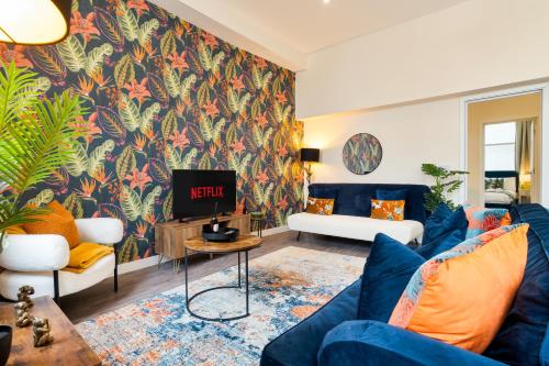 a living room with a blue couch and a tv at Spacious Luxury 2 Bedroom City Centre Apartment with Terrace & High Ceiling in Canterbury