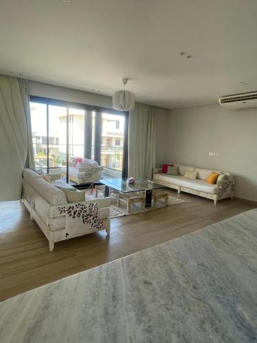 a living room with white furniture and a large window at Almaza Bay in Alexandria