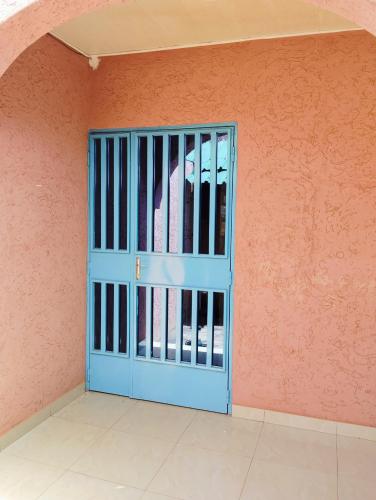 a blue door in a room with a pink wall at Confort hébergement in Ouagadougou