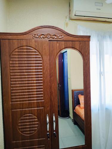 a wooden cabinet with a mirror in a room at Confort hébergement in Ouagadougou