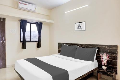a bedroom with a black and white bed and a window at Hotel O Paradise Inn in Pune