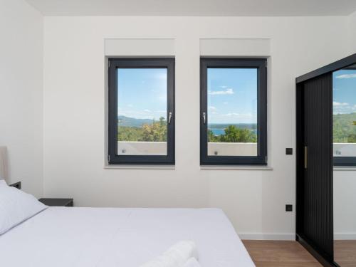 a bedroom with three windows and a white bed at Holiday Home Sime by Interhome in Maslenica