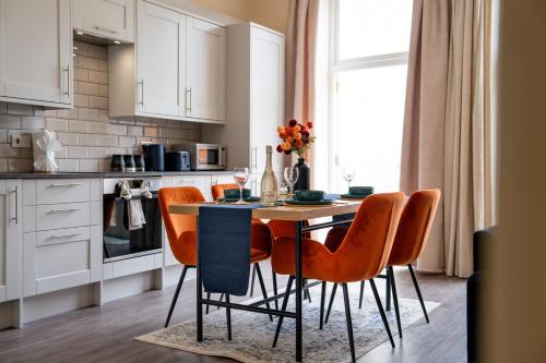 a kitchen with a wooden table and orange chairs at Spacious Luxury 2 Bedroom City Centre Apartment with Terrace & High Ceiling in Canterbury