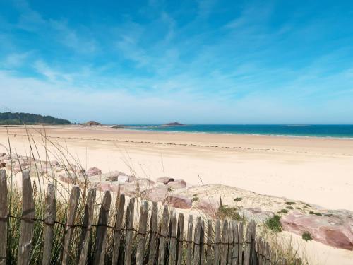 a fence on a beach with the ocean in the background at Holiday Home Le petit Papeu by Interhome in Frehel