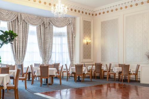 a dining room with tables and chairs and a chandelier at The Grand Burstin Hotel in Folkestone