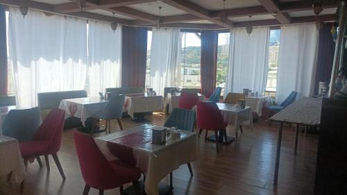 a dining room with tables and chairs and windows at SaraSofi Hotel in Baku
