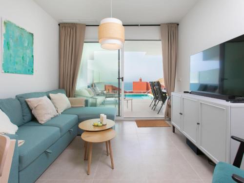 a living room with a blue couch and a tv at Apartment Heaven Free Spa & Padel by Interhome in Torrox Costa