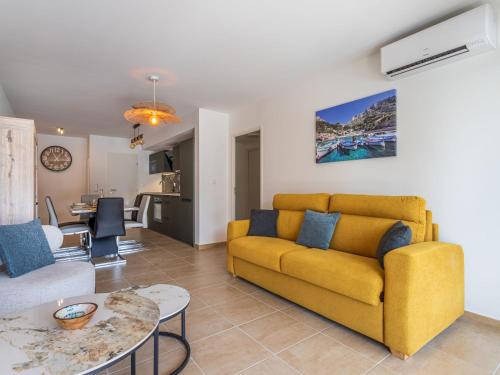 ein Wohnzimmer mit einem gelben Sofa und einem Tisch in der Unterkunft Apartment Les Pins Parasols by Interhome in Bormes-les-Mimosas