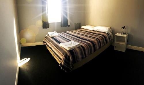 a small bedroom with a bed with a window at Kearsley Hotel in Cessnock
