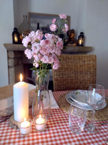 a table with a candle and flowers in a vase at Les Chambres du 11 - Chambres et Table d'hôtes in Chevigny