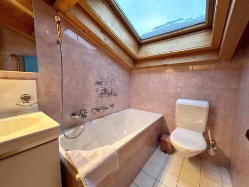 a bathroom with a tub and a toilet and a window at Gstaad Blue Sky Chalet with stunning views in Gstaad