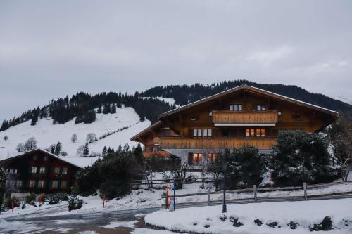 a large wooden building with snow on the ground at Gstaad Blue Sky Chalet with stunning views in Gstaad