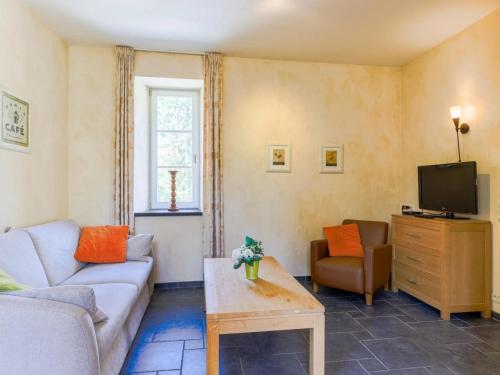 a living room with a couch and a tv at Cozy Apartment in a 16th Century Castle in Aywaille