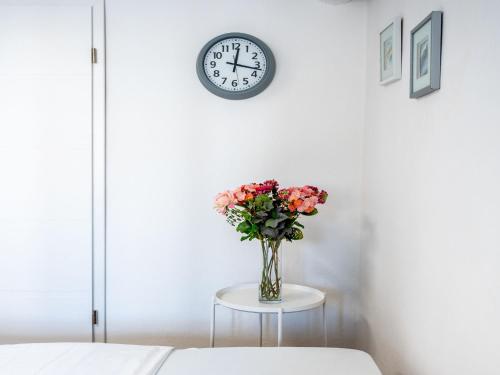 a vase of flowers on a table under a clock at Apartment Adelsberg Inn-2 by Interhome in Postojna
