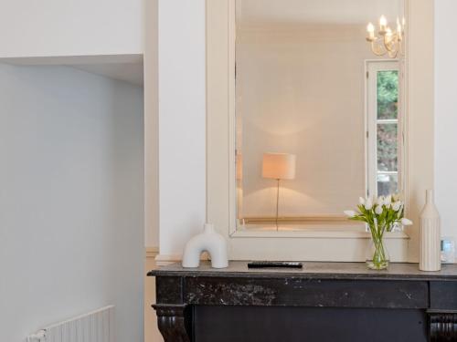 a room with a mirror and a dresser with flowers at Holiday Home Maison de ville by Interhome in Deauville
