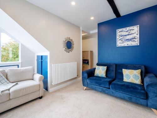 a living room with a blue couch and a chair at Holiday Home Cherry Orchards by Interhome in Mevagissey