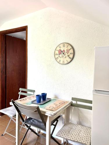 a table with chairs and a clock on a wall at Mansarda apartment in Kotor