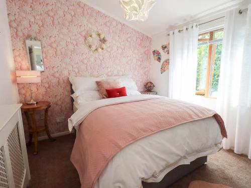 a bedroom with a large bed with pink wallpaper at Charnwood in Carnforth