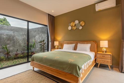 a bedroom with a bed and a large window at Villa Sattvika in Kerobokan